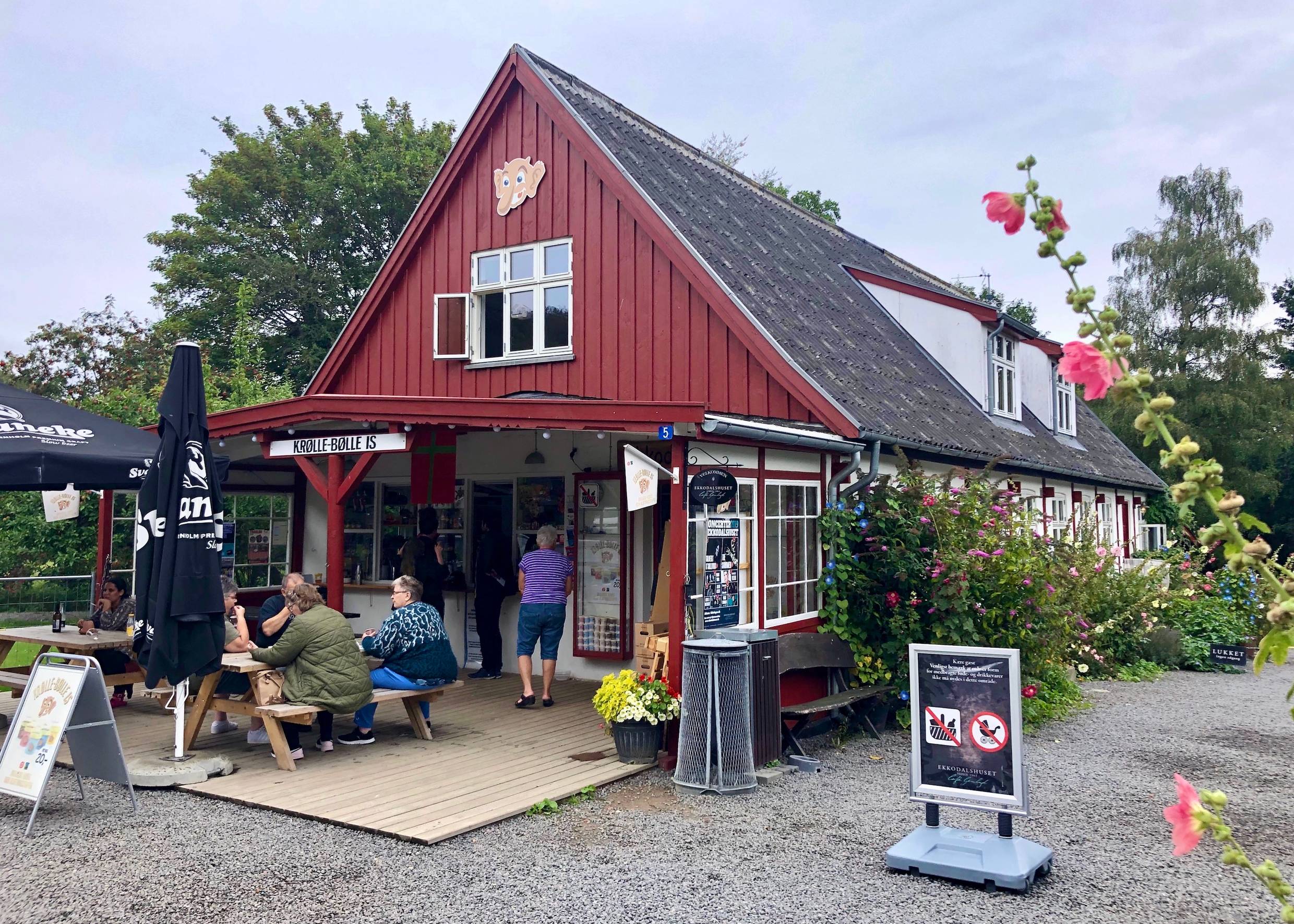 Gäste vor einem roten Holzhaus mit einem Imbiss