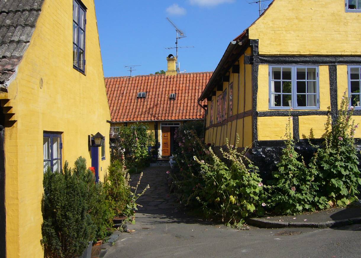 Schmale Gassen mit gelben Fachwerkhäusernund üppigen Blumen vor den Häusern