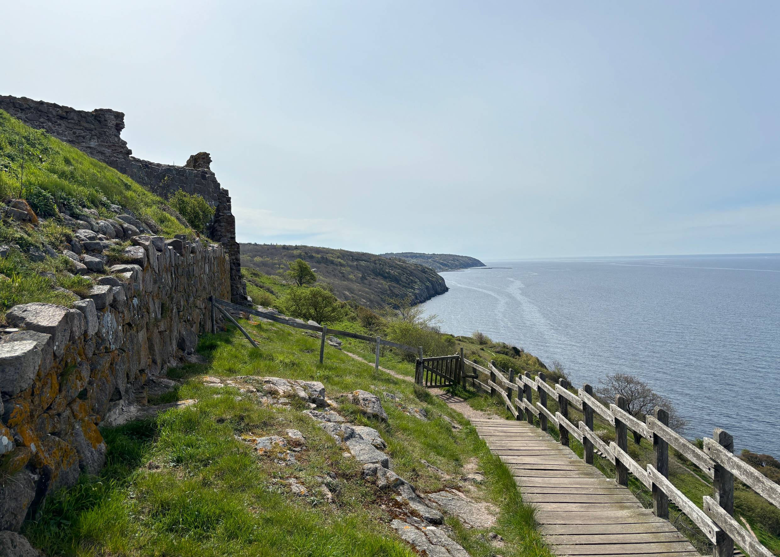 Holztreppe am Meer entlang und eine kleine Pforte, die auf einem Wanderweg führt