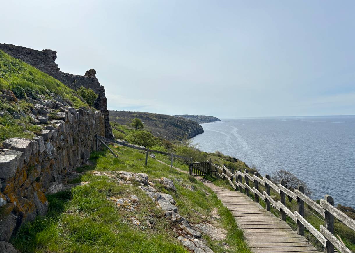 Holztreppe am Meer entlang und eine kleine Pforte, die auf einem Wanderweg führt