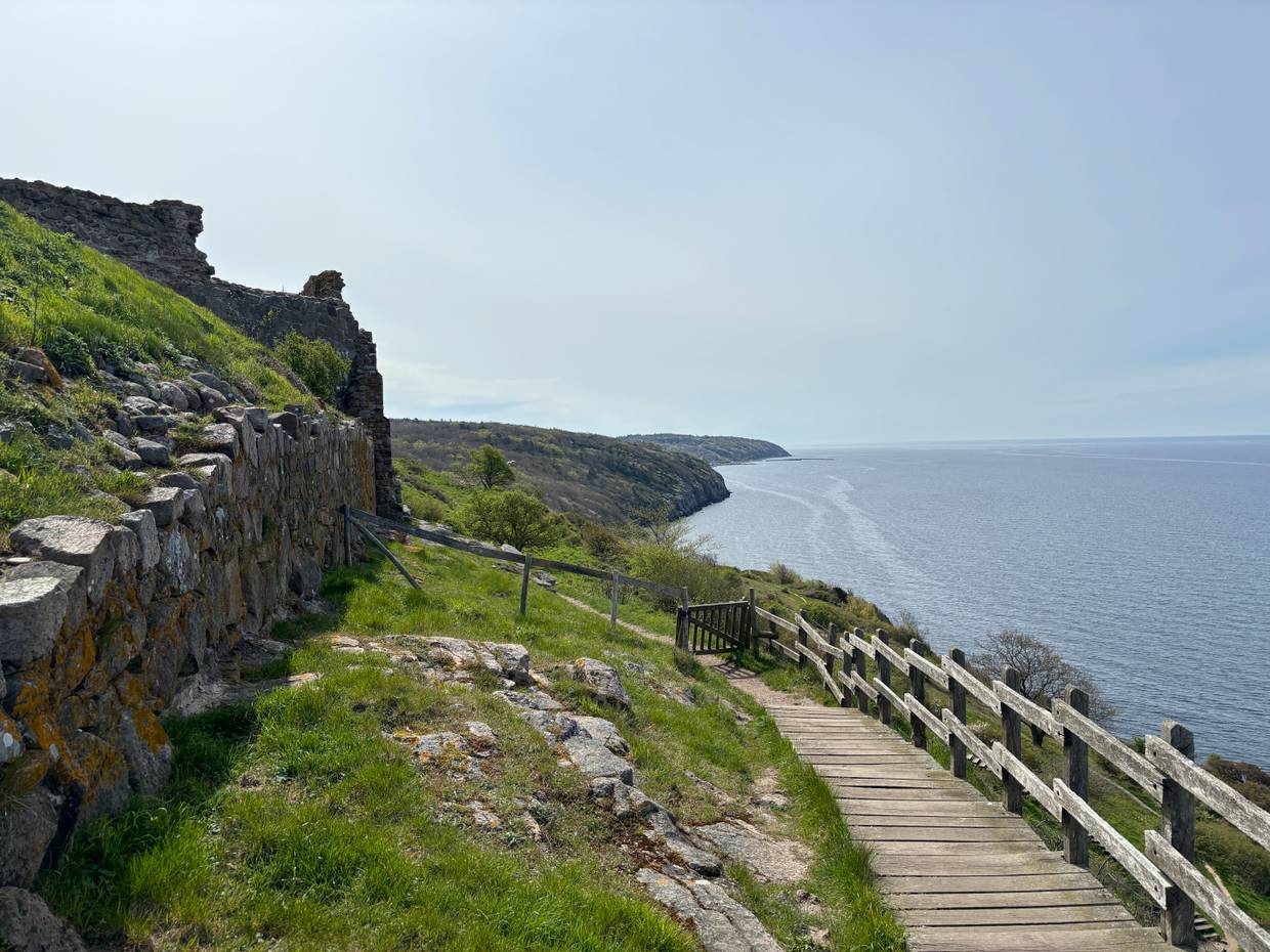 Holztreppe am Meer entlang und eine kleine Pforte, die auf einem Wanderweg führt