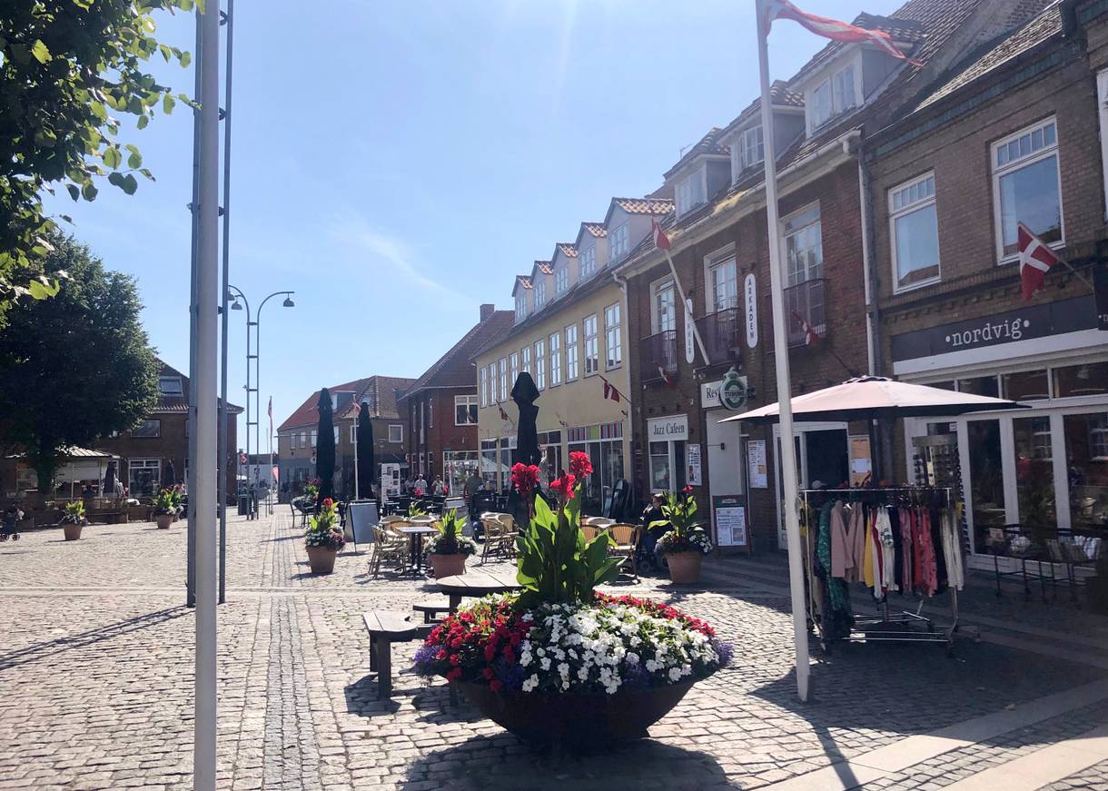 Fußgängerzone mit großen Blumenkübeln und einigen Geschäften