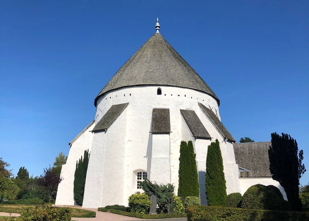 Weiße Rundkirche mit grauen Holzschindeln auf dem Dach