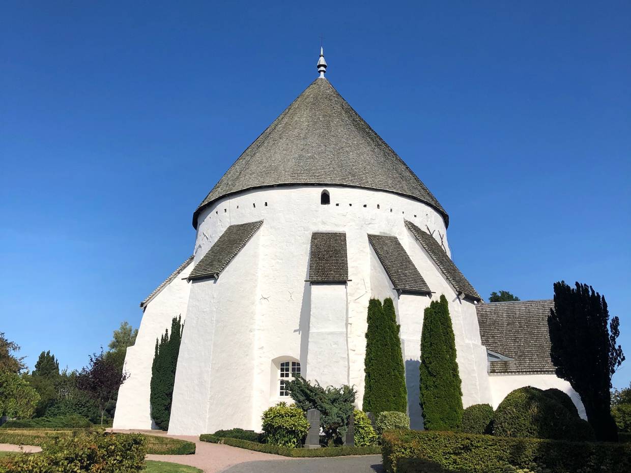 Weiße Rundkirche mit grauen Holzschindeln auf dem Dach