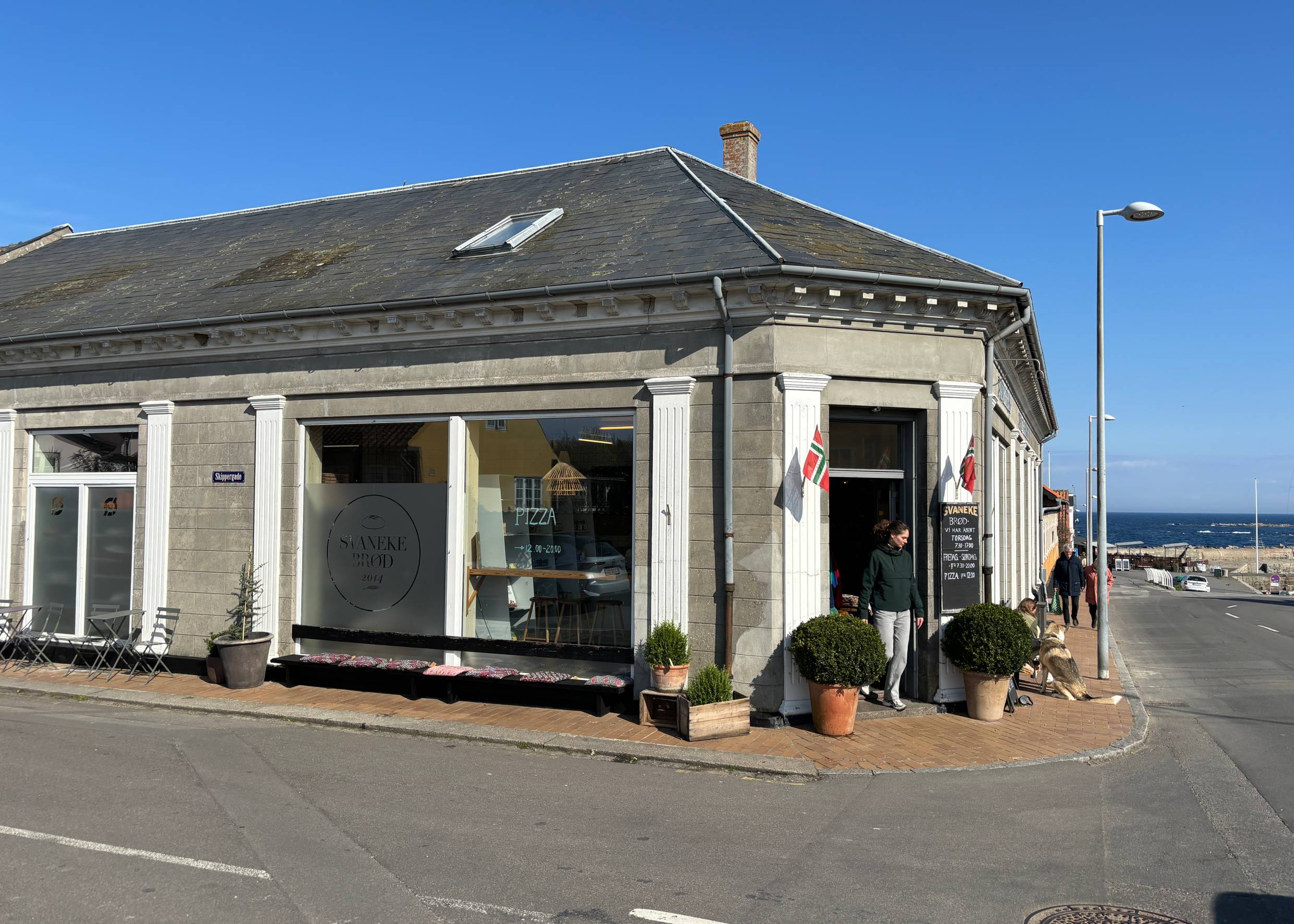 Bäckerei in einem Eckhaus am Hafen mit norwegischen Flaggen am Eingang
