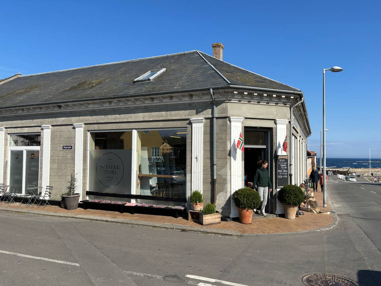 Bäckerei in einem Eckhaus am Hafen mit norwegischen Flaggen am Eingang