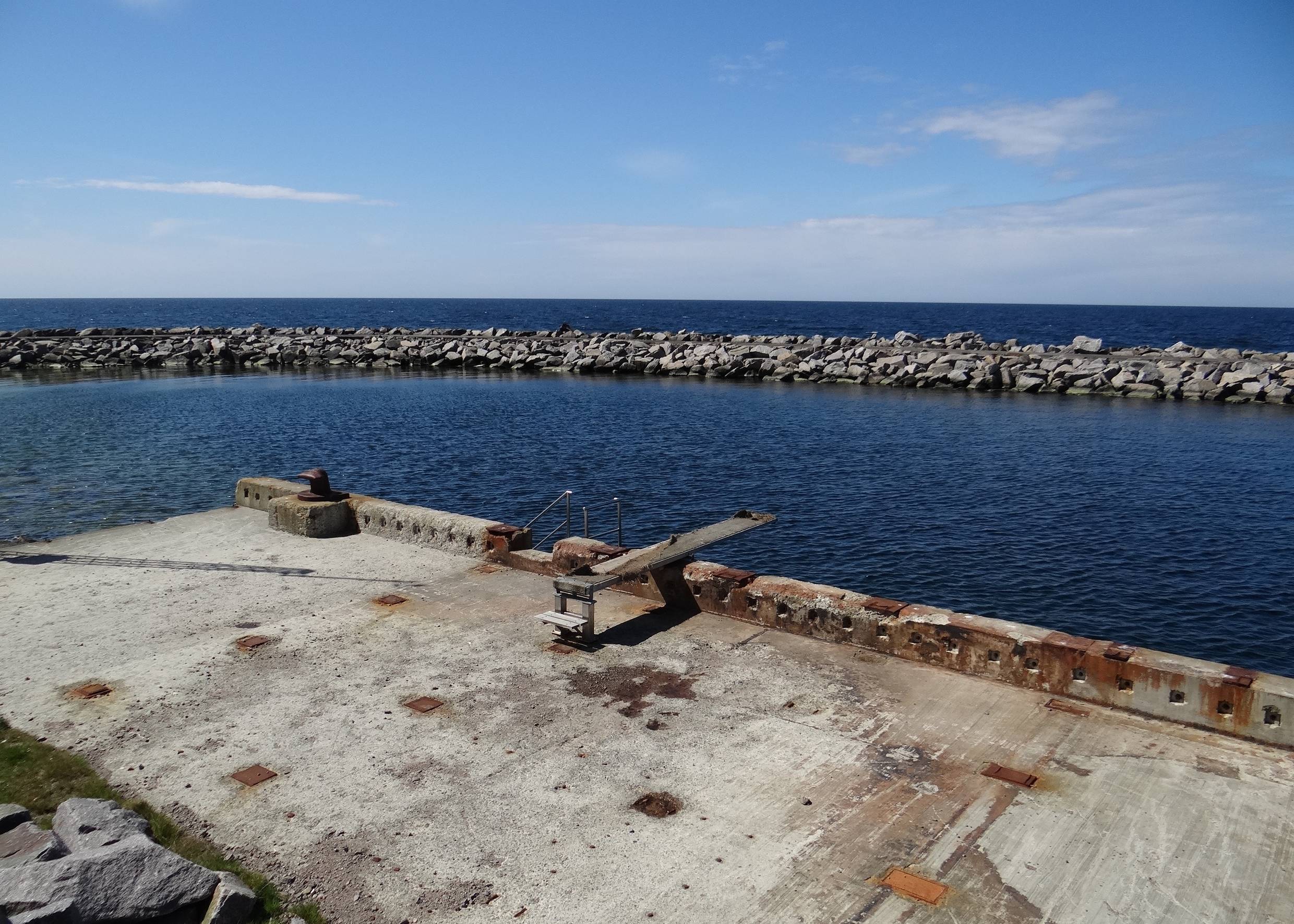 Sprungbrett an einer etwas rostigen Kaimauer in einem verlassenen Hafen