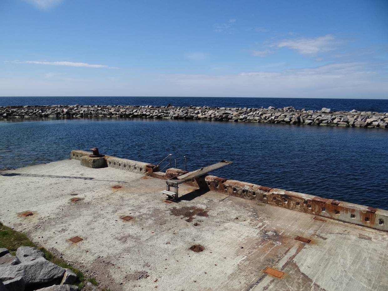 Sprungbrett an einer etwas rostigen Kaimauer in einem verlassenen Hafen