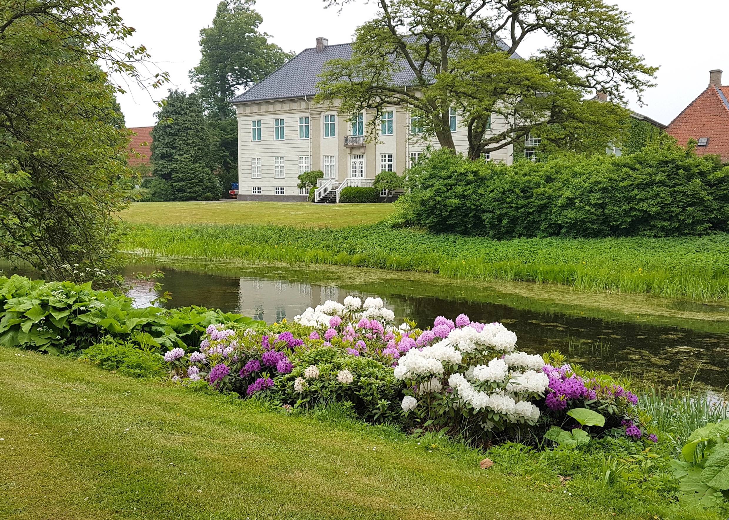 Großer Garten mit Blumen und Wasser im Vordergrund