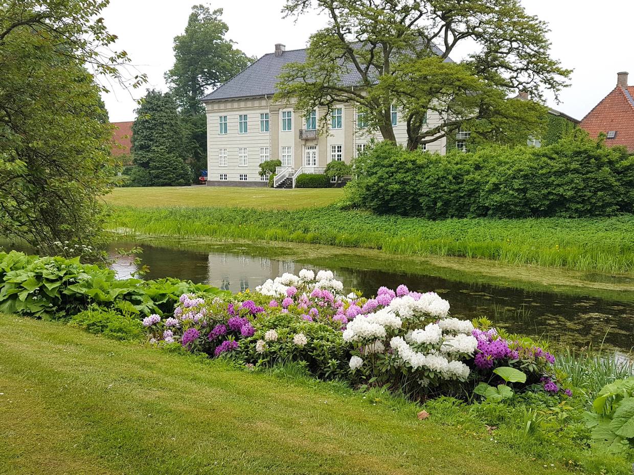 Großer Garten mit Blumen und Wasser im Vordergrund