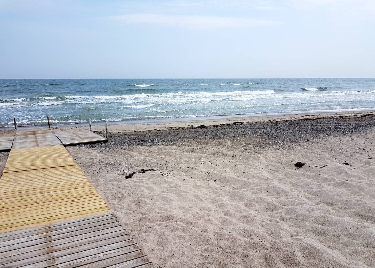 Holzsteg auf dem Strand bis zum Wasser