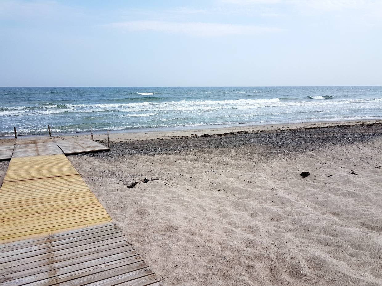 Holzsteg auf dem Strand bis zum Wasser