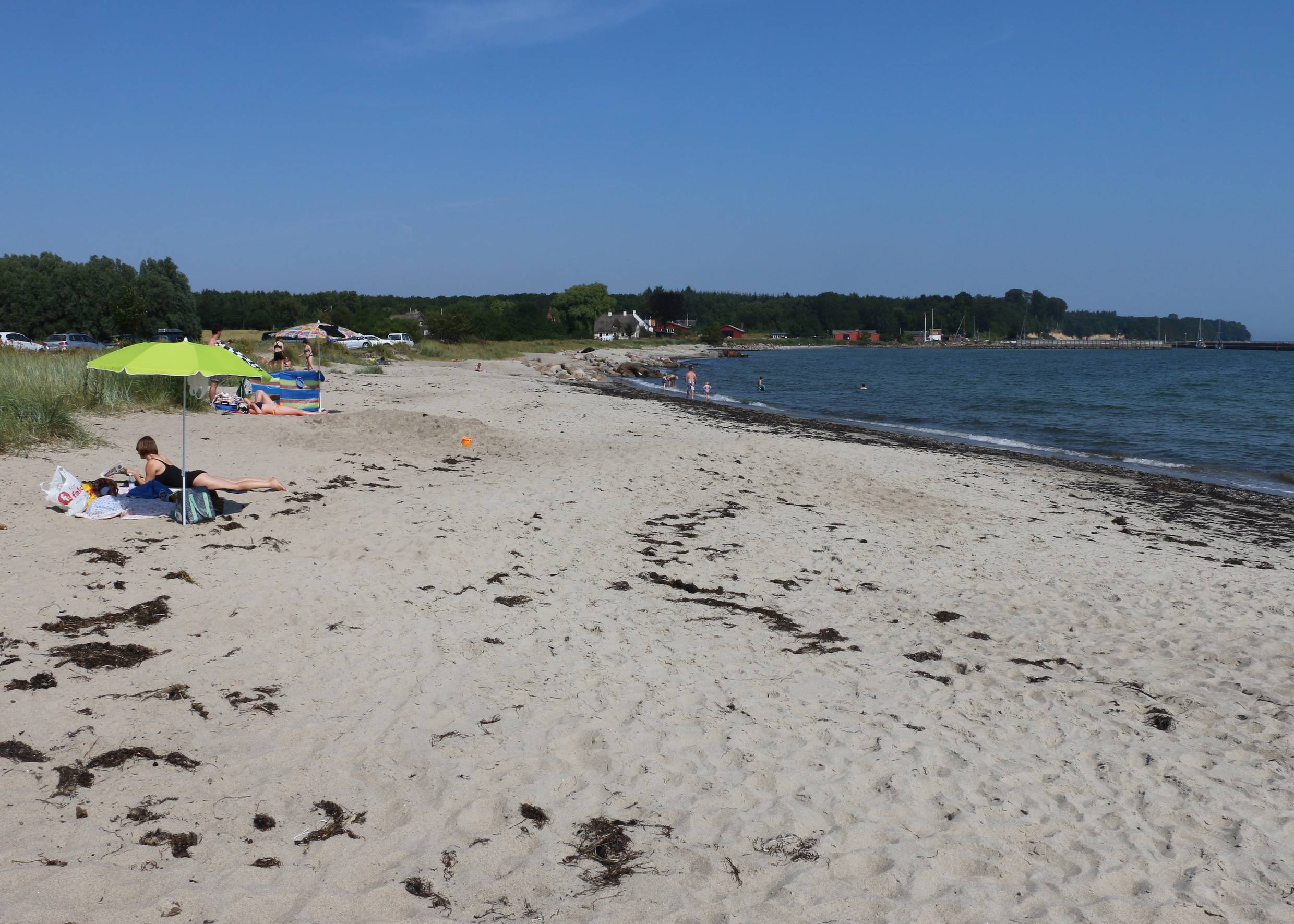 Sandstrand, im Hintergrund eine grüne Steilküste