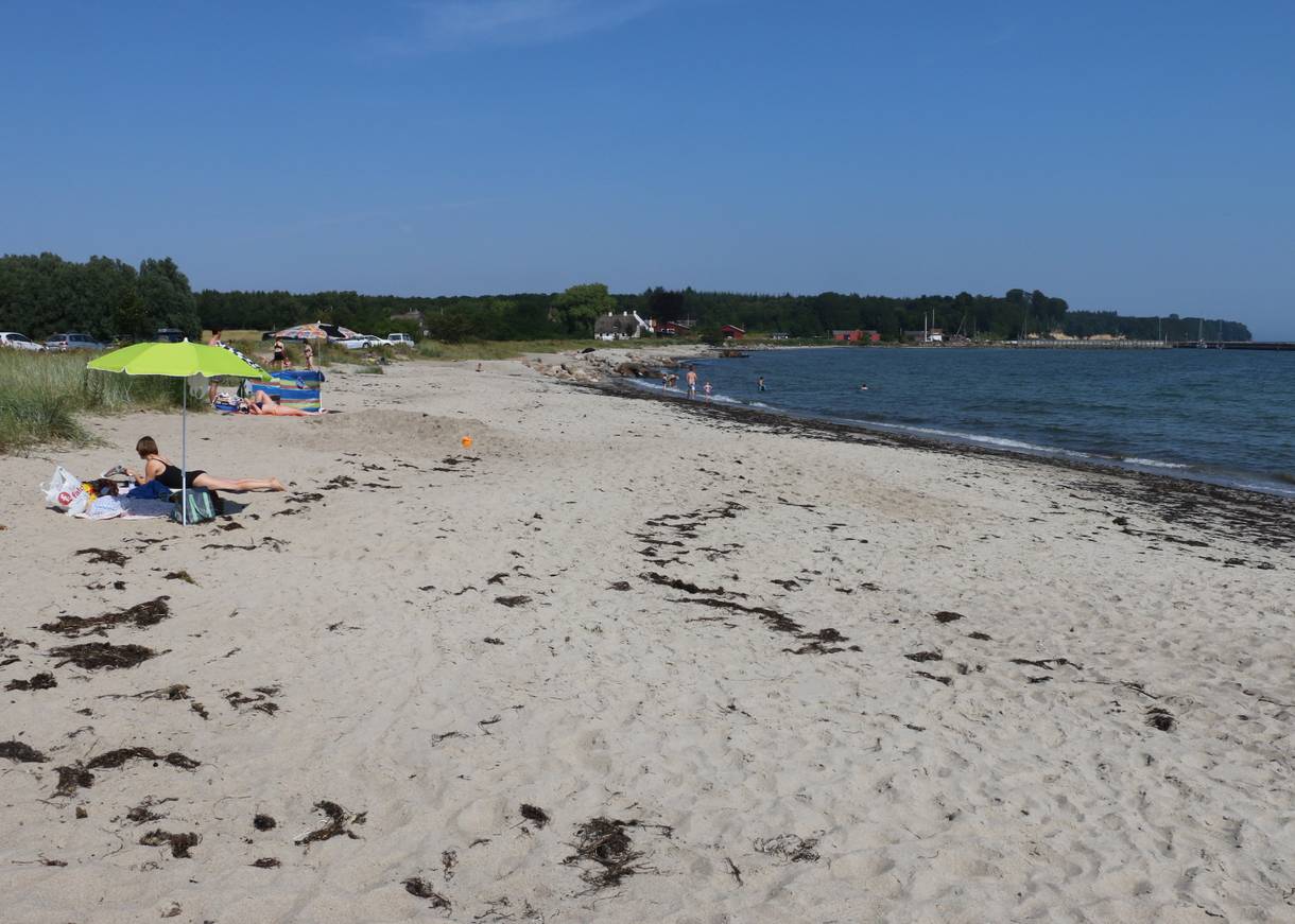 Sandstrand, im Hintergrund eine grüne Steilküste
