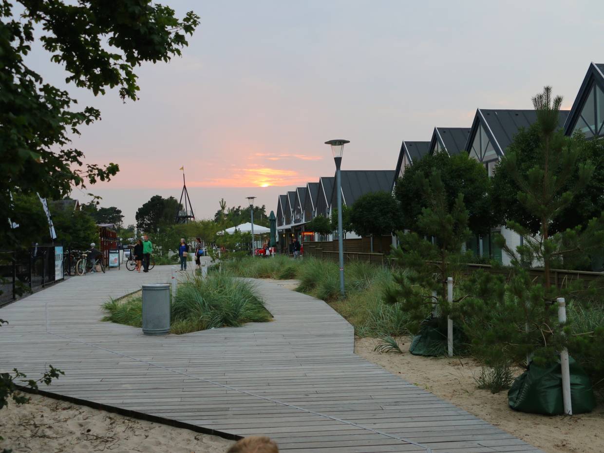 Sonnenuntergang hinter Häusern mit einem Promenade aus Holz im Vordergrund