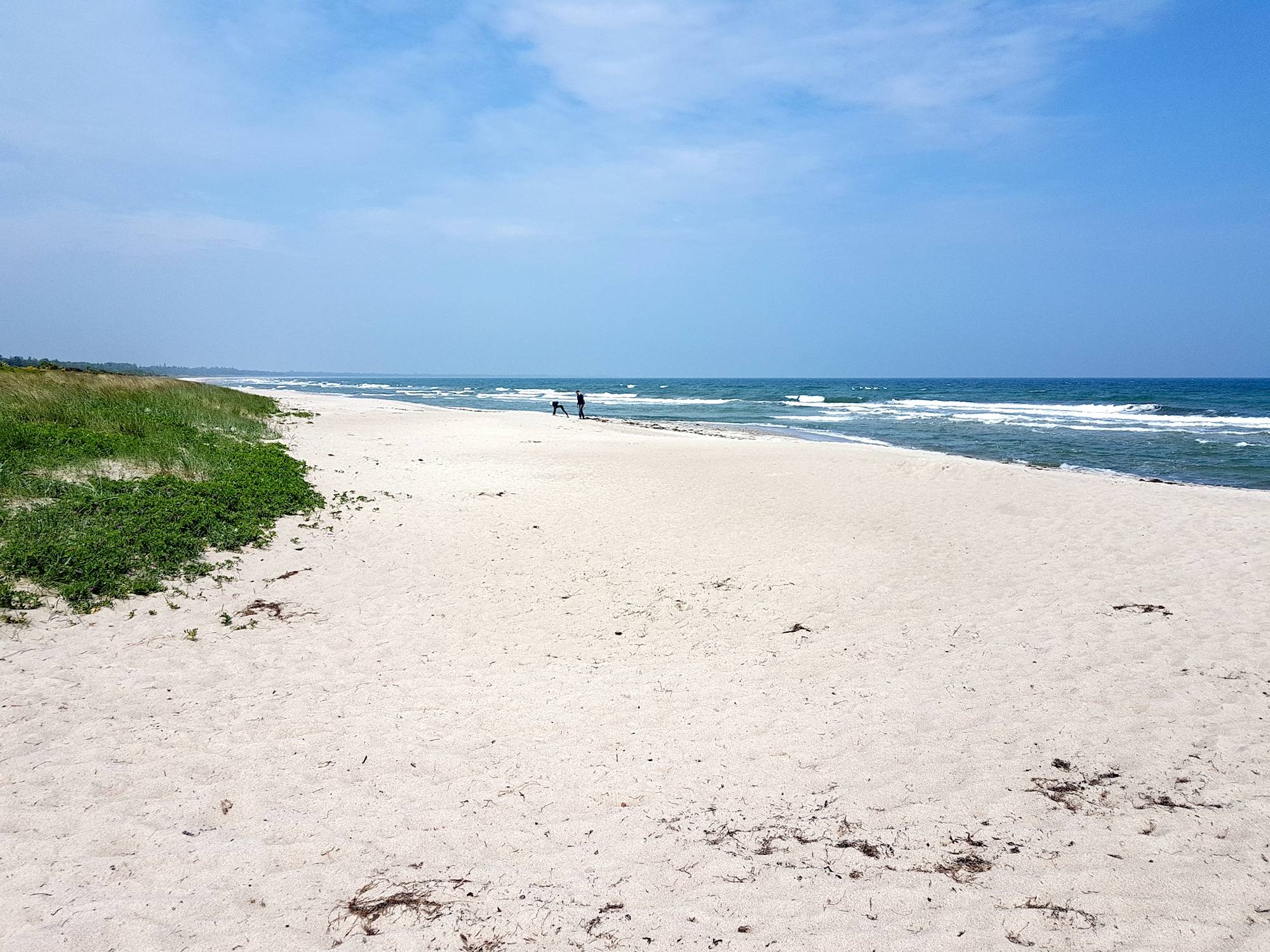 Sandstrand mit feinem, weißen Sand und Wellen im Hintergrund