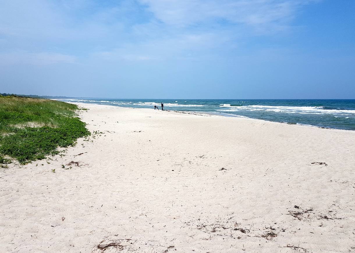 Sandstrand mit feinem, weißen Sand und Wellen im Hintergrund