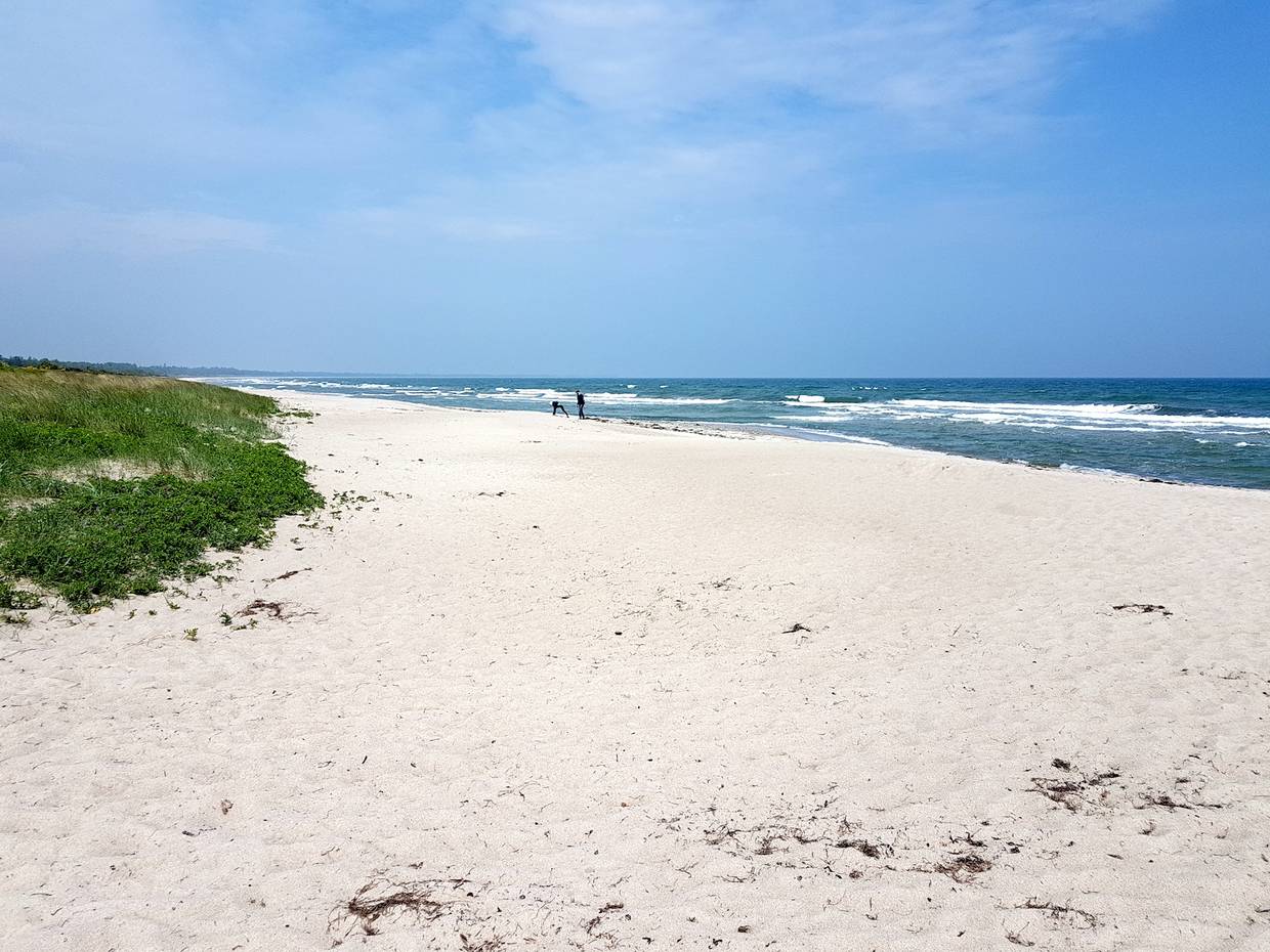 Sandstrand mit feinem, weißen Sand und Wellen im Hintergrund