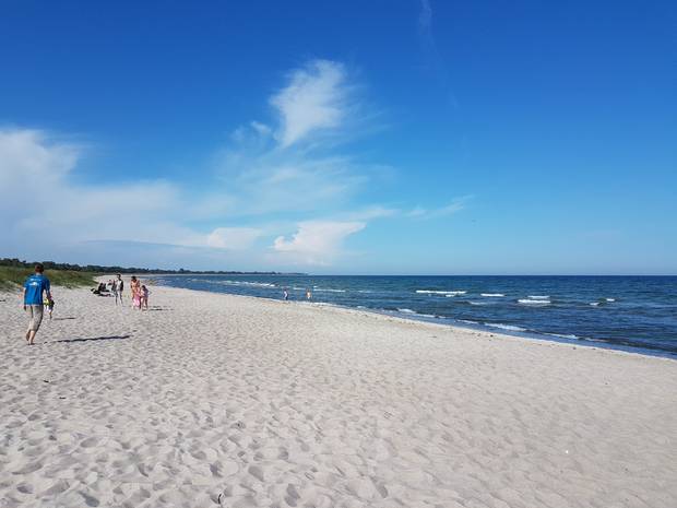 Weißer Sandstrand mit wenig Leute und kleine Wellen
