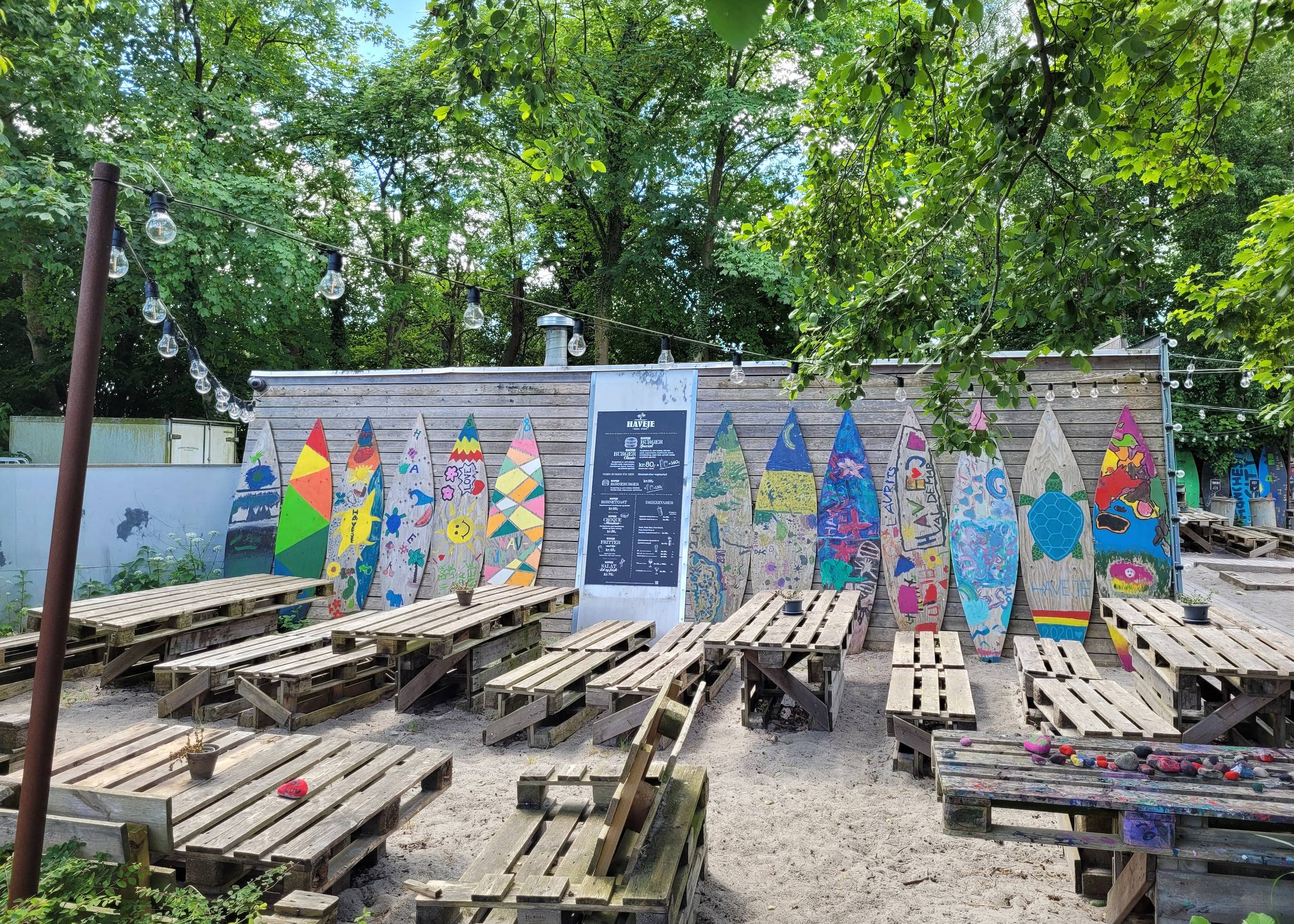 Strandbar mit Palettenmöbeln und bunten Surfboards als Deko