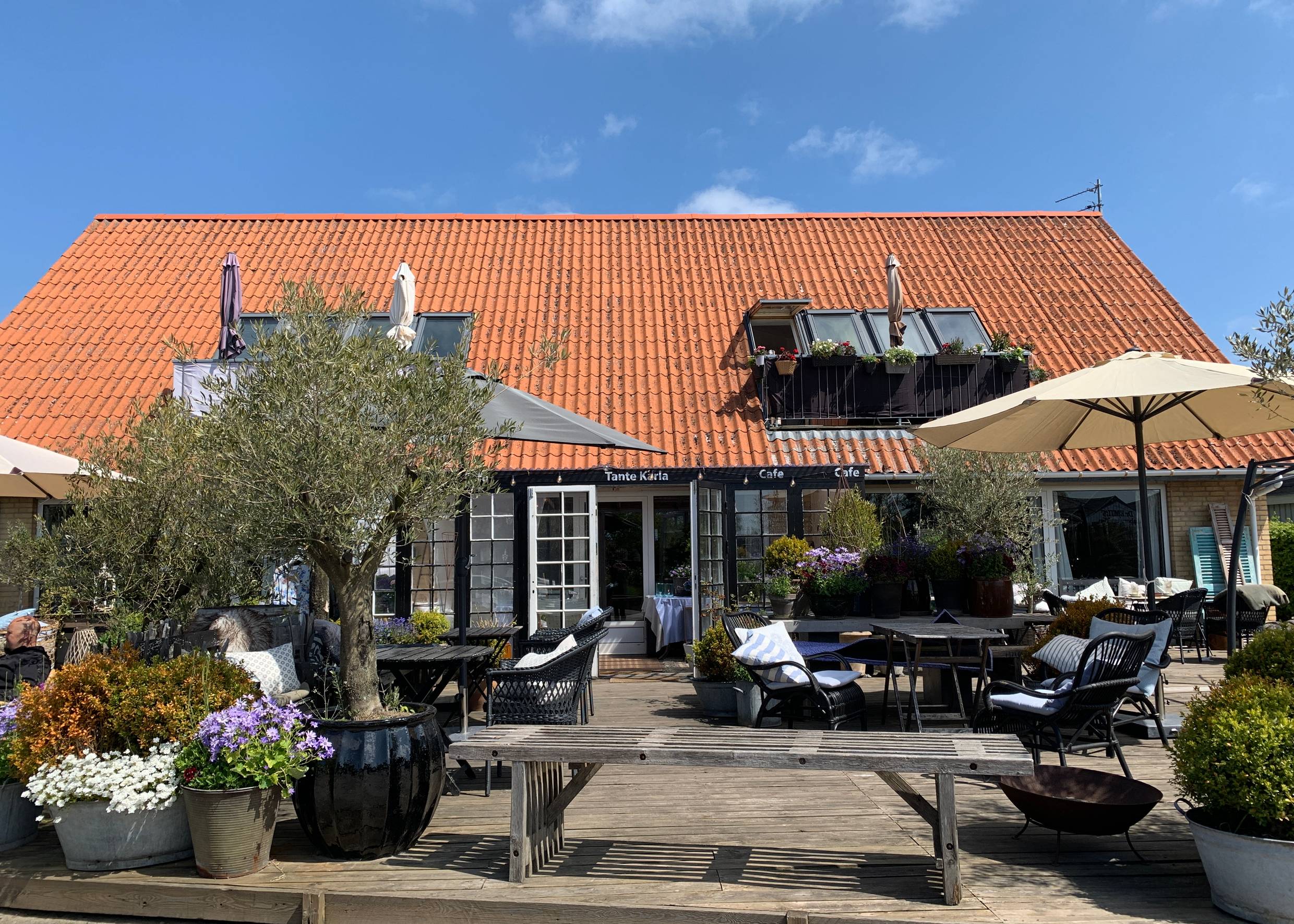 Café-Terrasse mit vielen Blumen und Gartenmöbeln