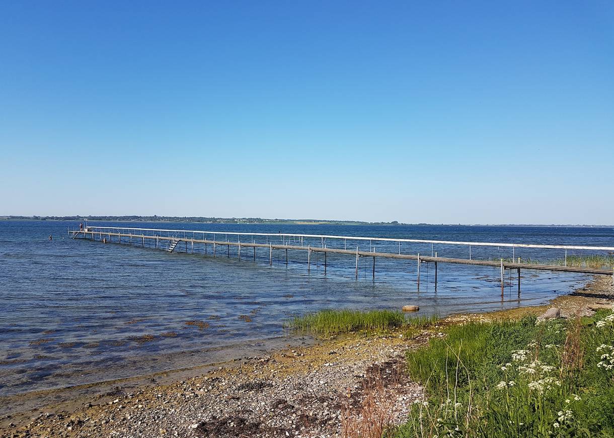 Langer Badesteg an einer steinigen Küste