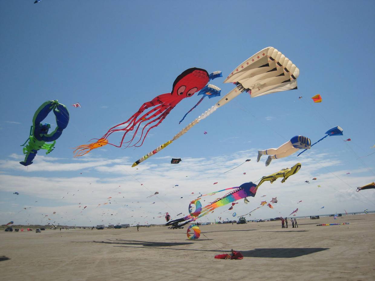Sehr große, bunte Drachen am Himmel über dem Strand