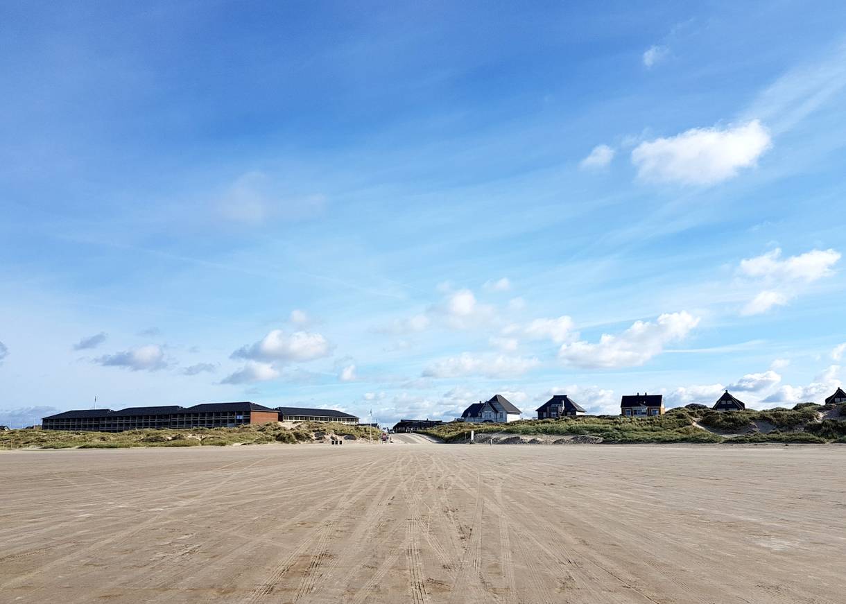Blick von Strand auf eine Zufahrt zwischen ferienhäusern und Dünen