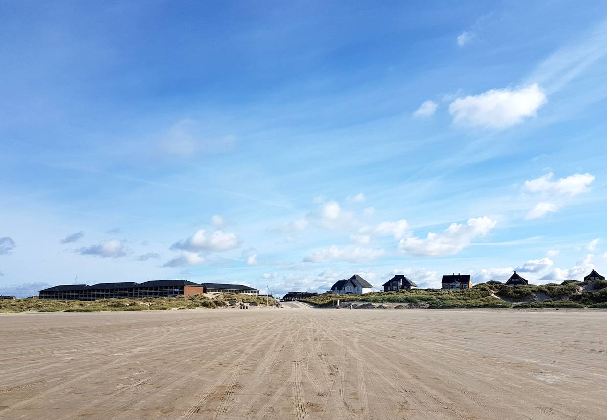 Blick von Strand auf eine Zufahrt zwischen ferienhäusern und Dünen