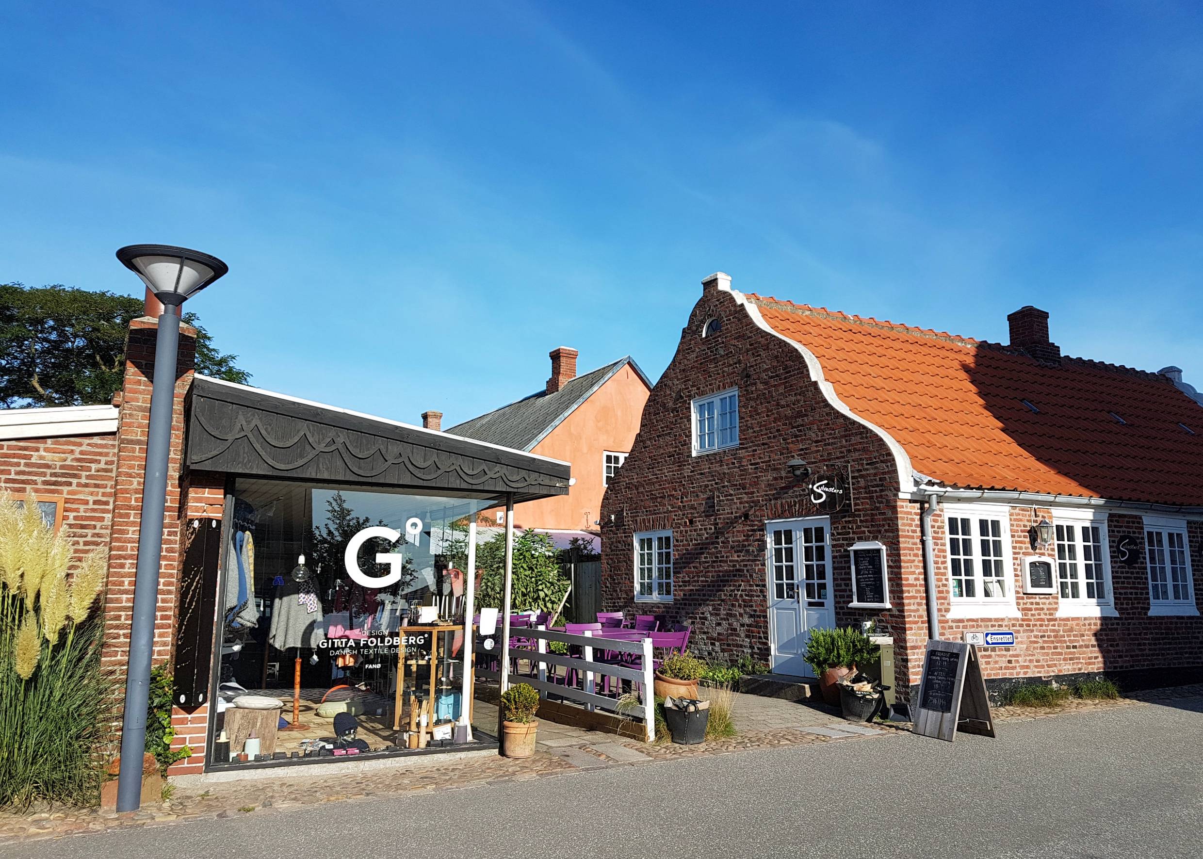 Zwei Eckhäuser, eine Boutique mit großen Schaufenstern und ein schmuckes Backsteinhaus mit einem Café