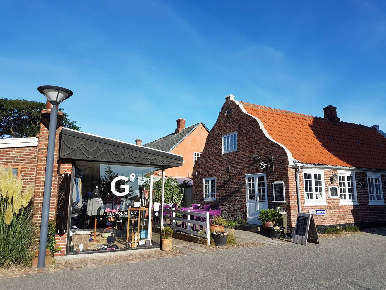 Zwei Eckhäuser, eine Boutique mit großen Schaufenstern und ein schmuckes Backsteinhaus mit einem Café
