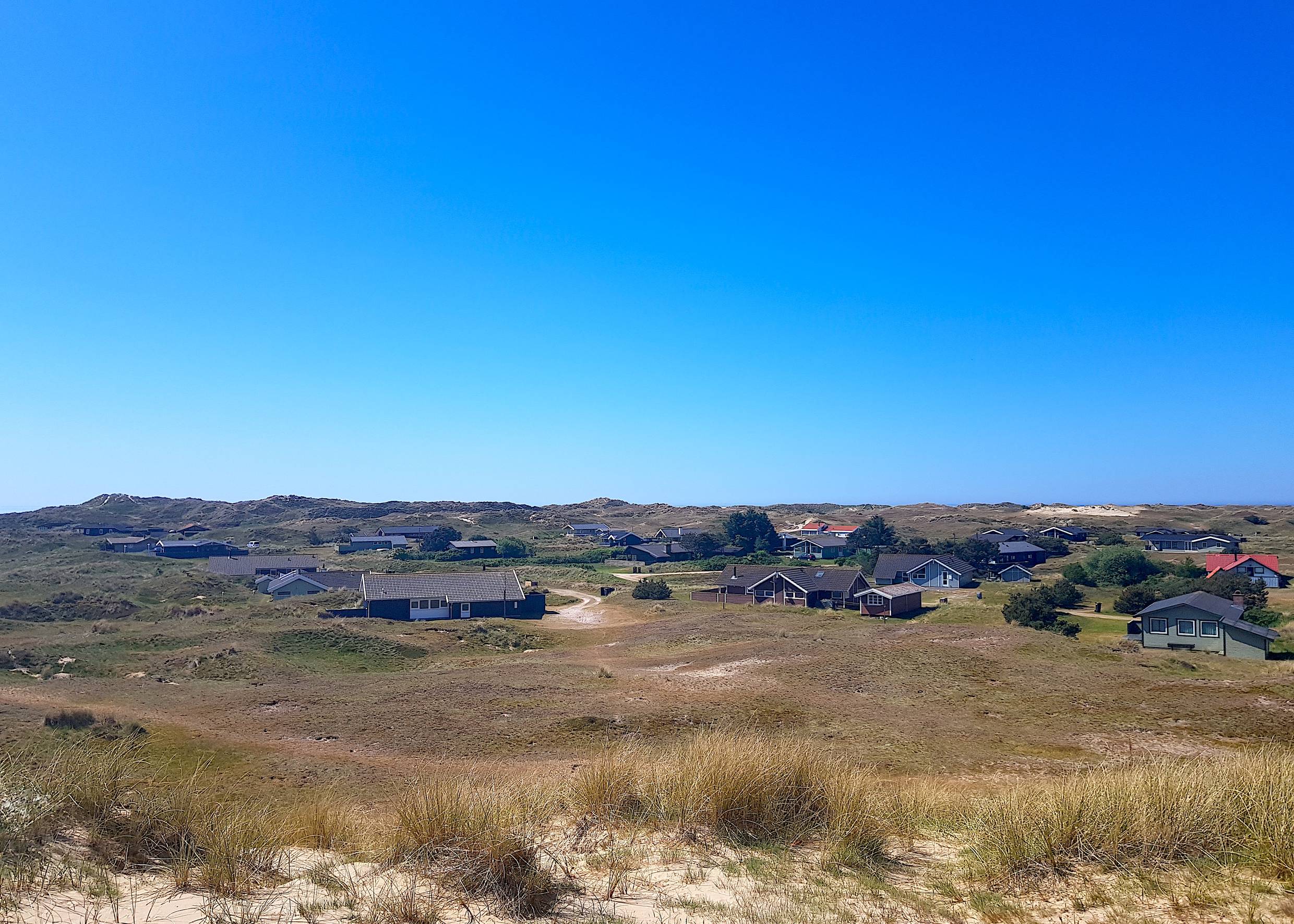 Blick auf eine Dünenlanfschaft am Meer mit zahllosen Ferienhäusern
