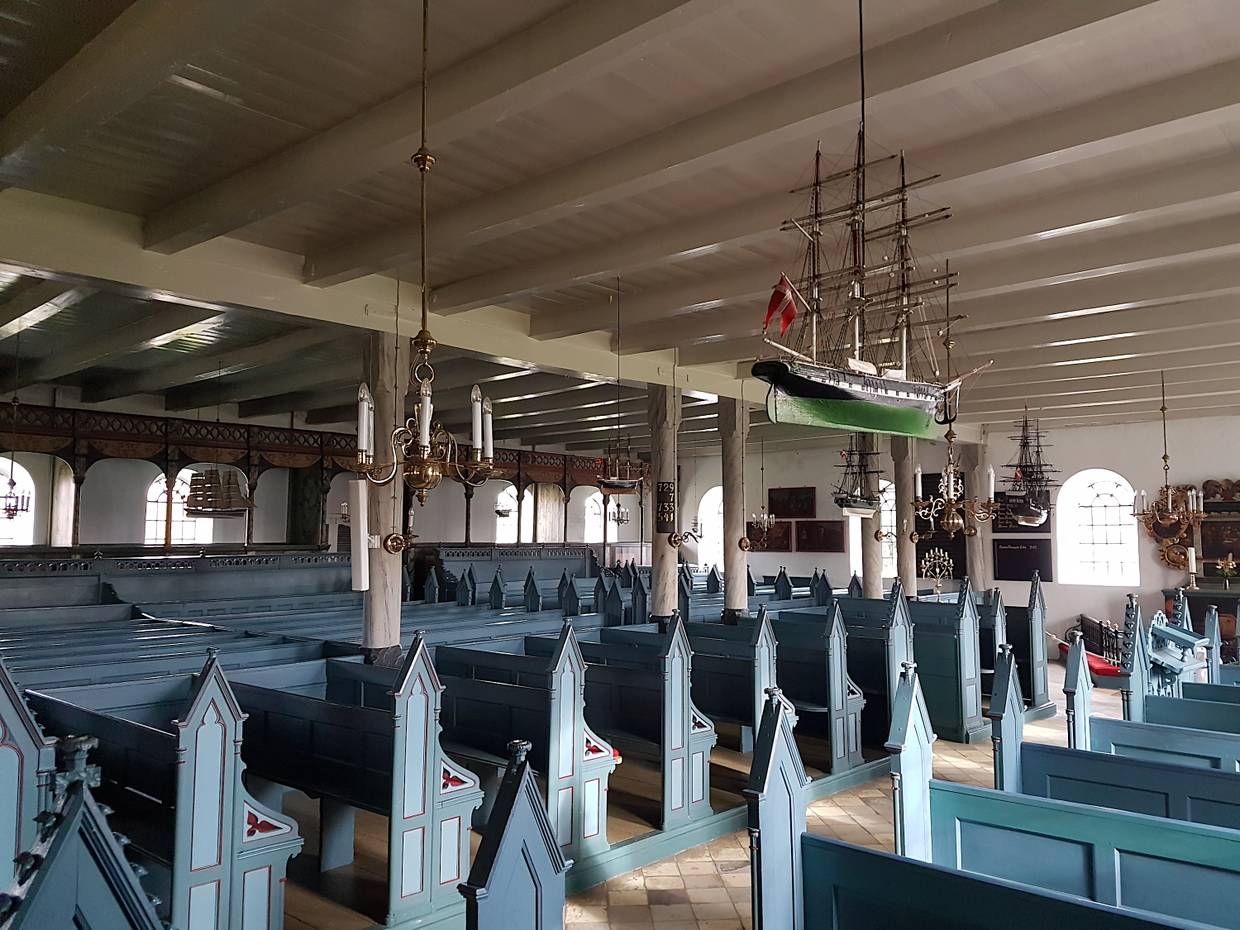 Innenraum einer flachen Kirche mit hellblauen Holzbänken