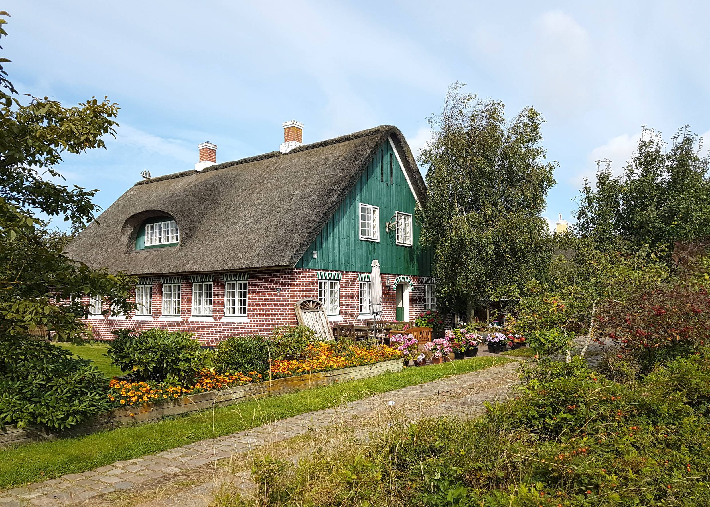 Rotes Reetdachhaus mit grünem Holzgiebel