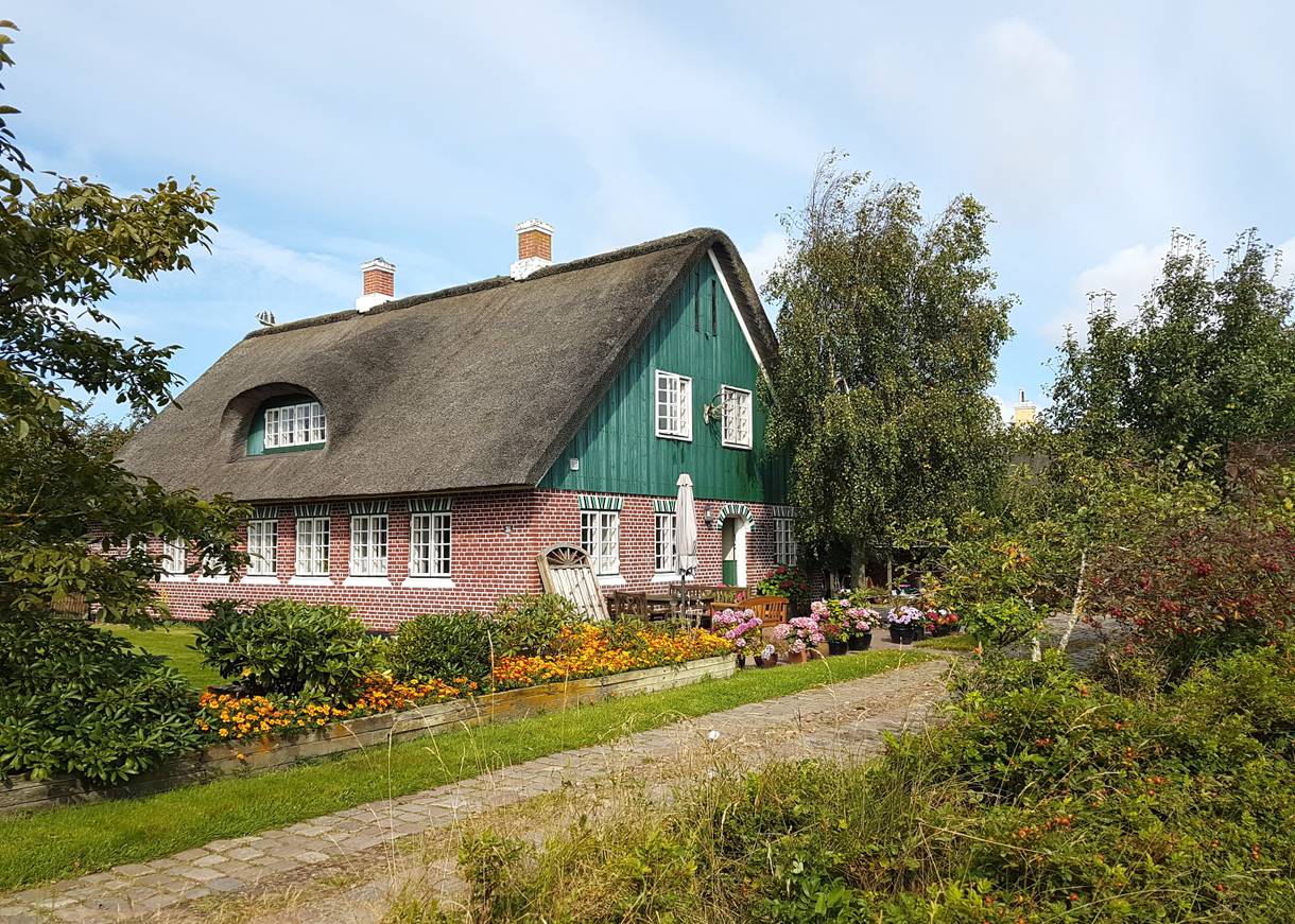 Rotes Reetdachhaus mit grünem Holzgiebel
