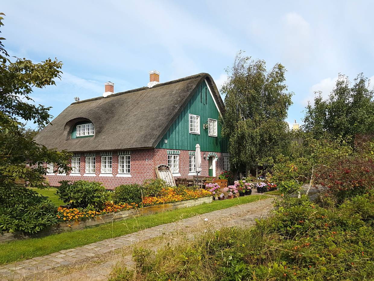 Rotes Reetdachhaus mit grünem Holzgiebel