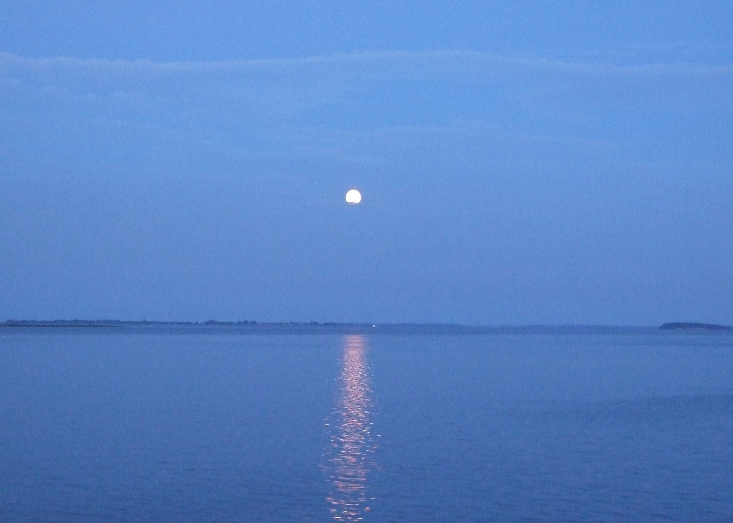 Blaues Licht bei Vollmond über dem windstillen Meer