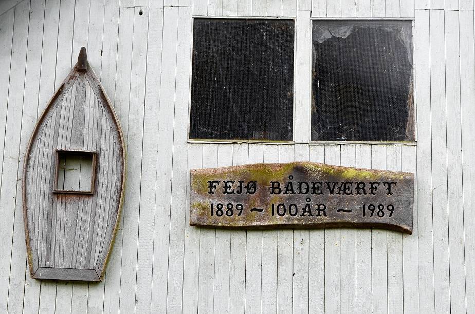 Graue Holzwand mit einem alten Schild mit Jahreszahlen zur Werft