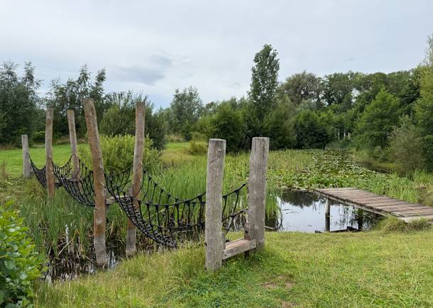 Blick auf einen See mit einer Kletterbrücke und einem Steg 