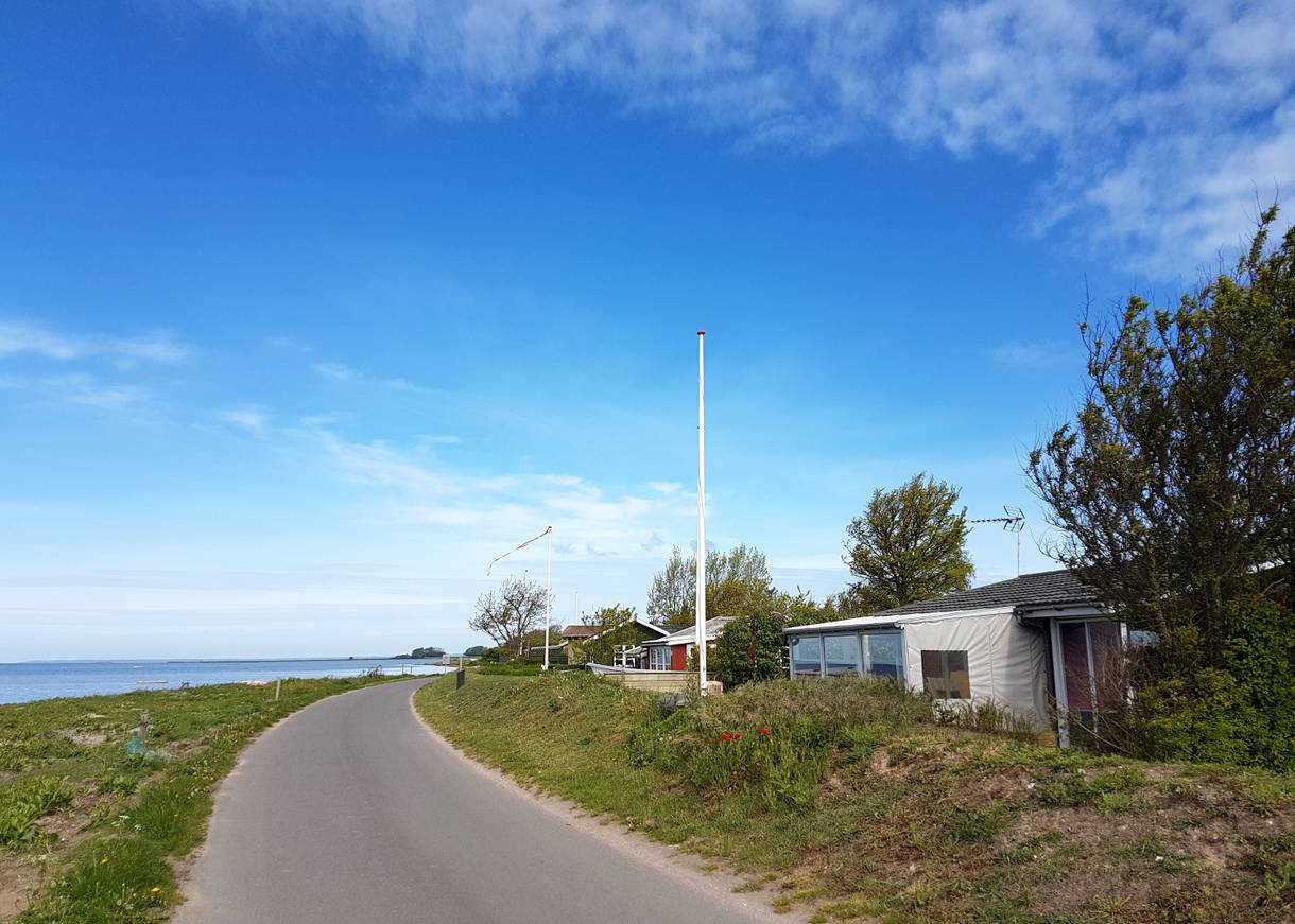 Schmale Straße zwischen Meer und kleinen Ferienhäusern