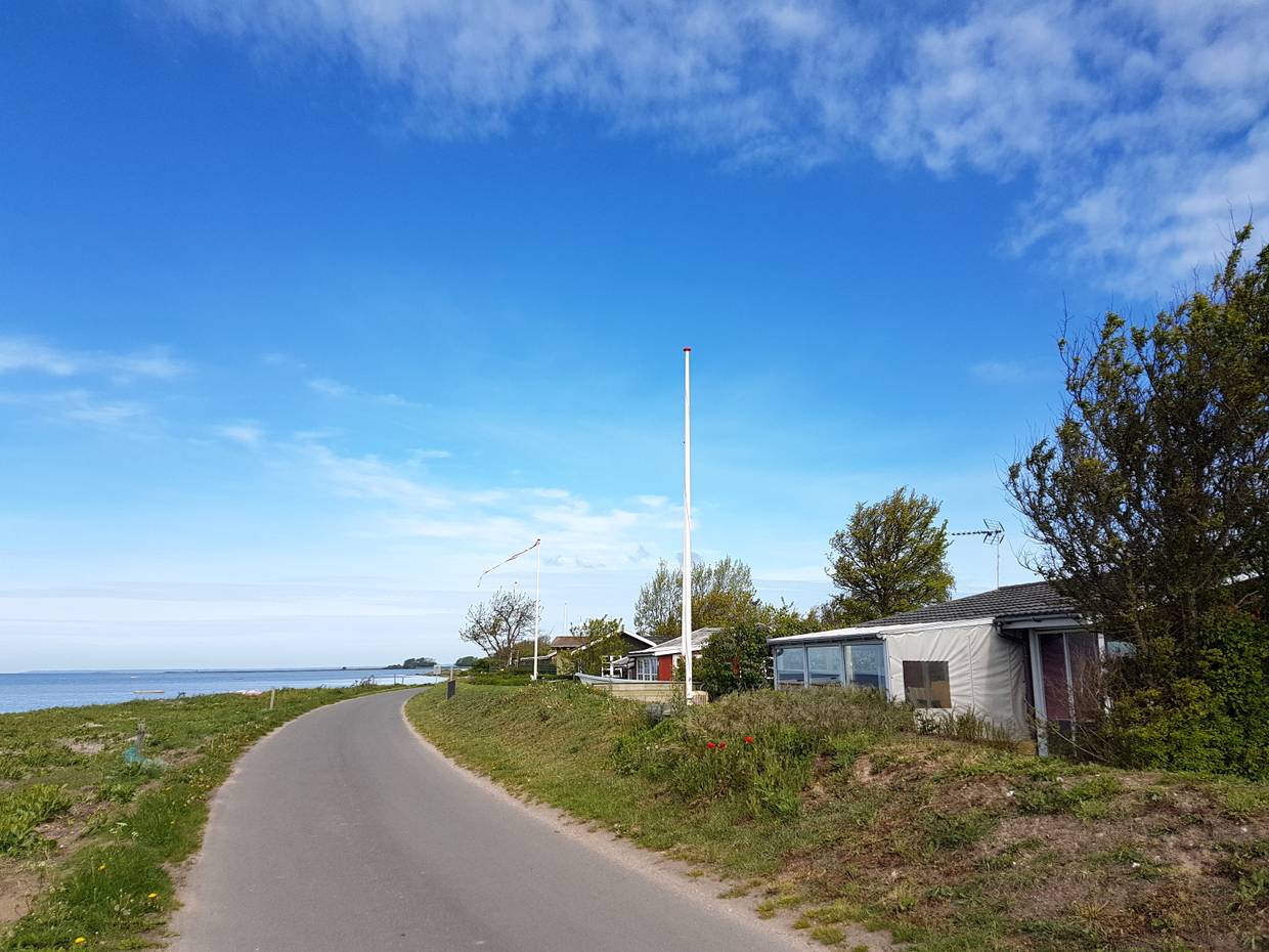 Schmale Straße zwischen Meer und kleinen Ferienhäusern