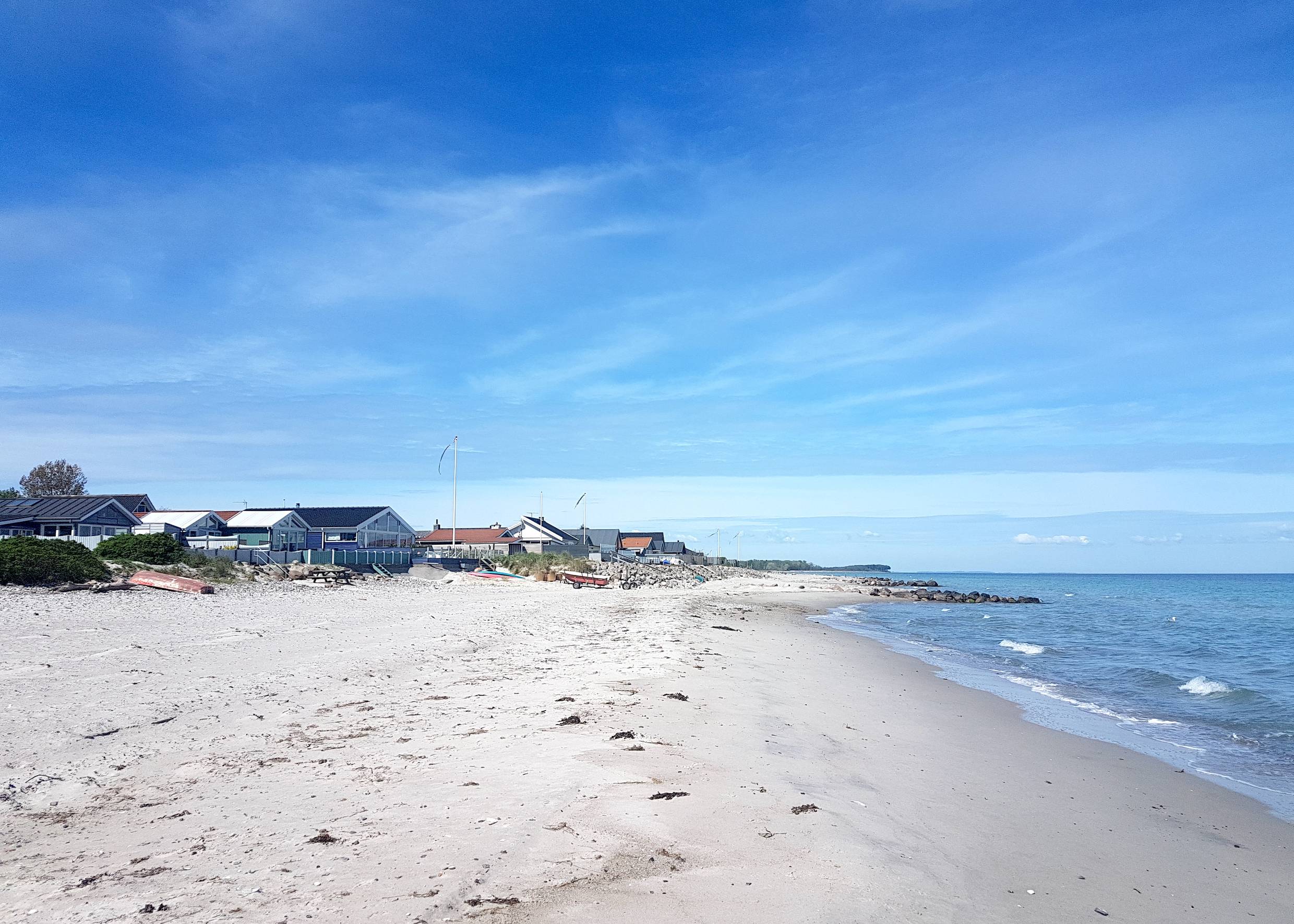 Ferienhäuser direkt am Strand in Dänemark, davor flache, blaue Ostsee
