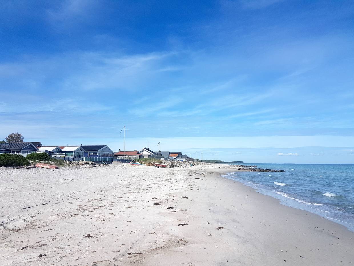 Ferienhäuser direkt am Strand in Dänemark, davor flache, blaue Ostsee