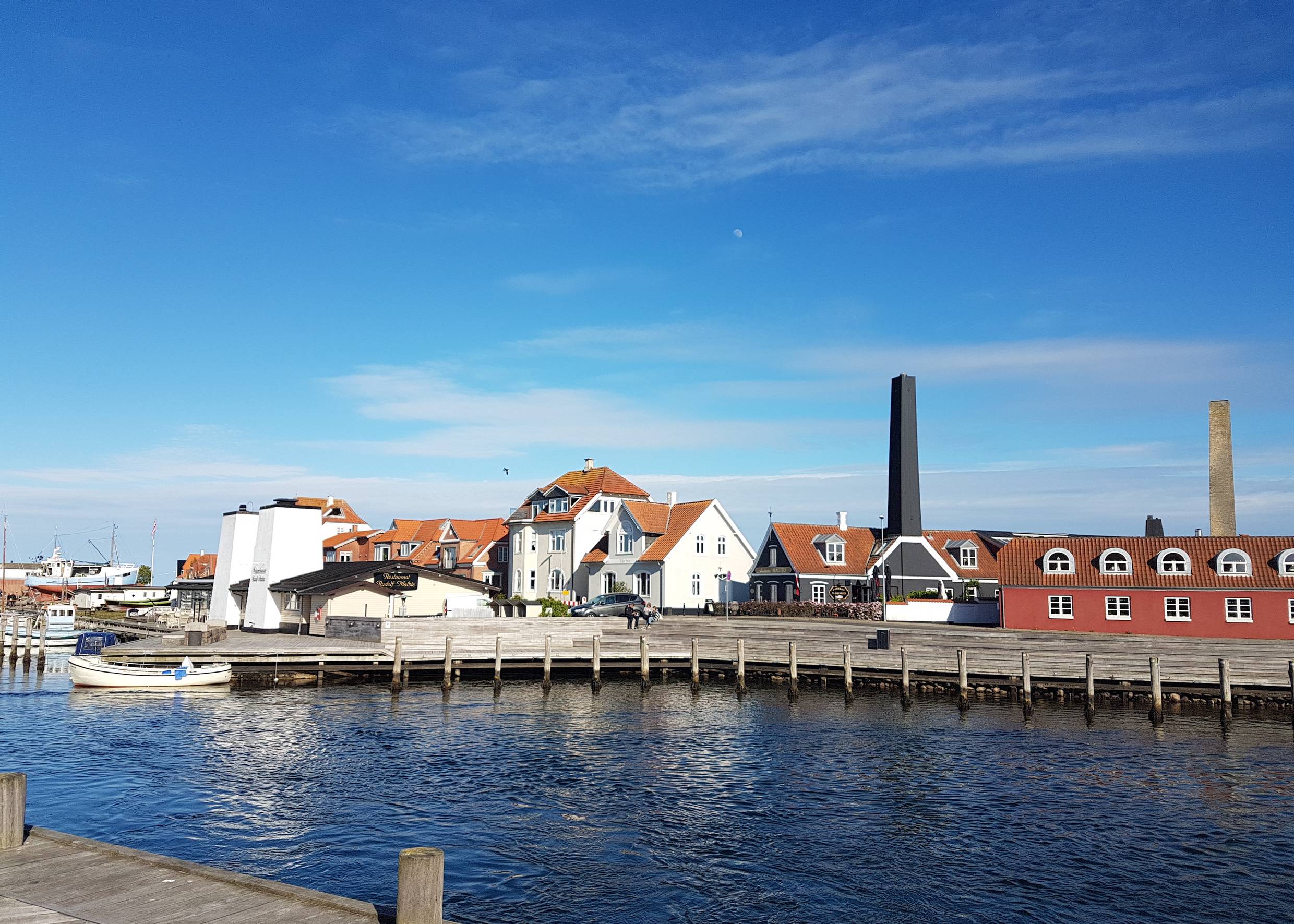 Holzstege an einem Hafen, dahinter verschiedene alte Häuser