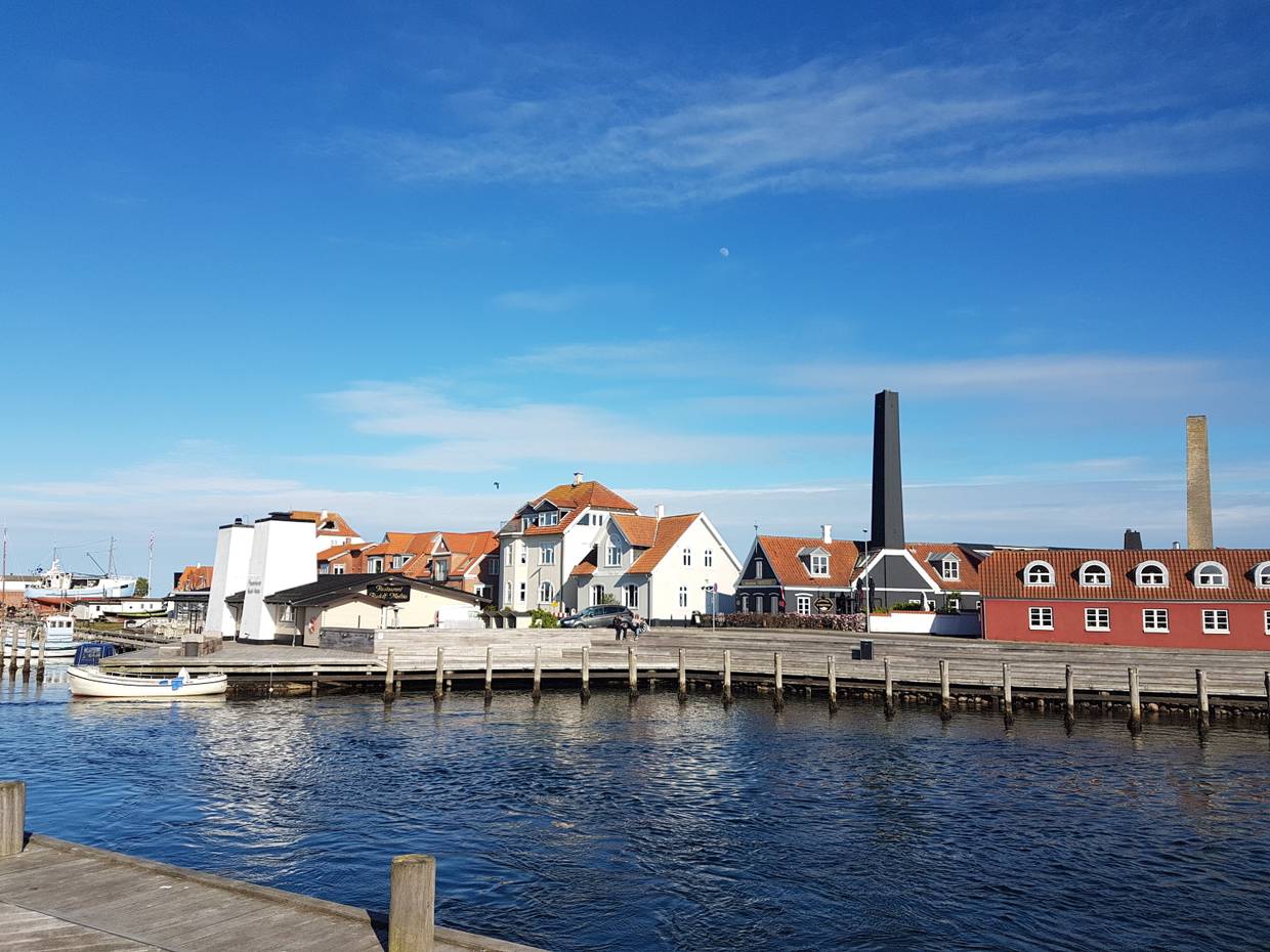 Holzstege an einem Hafen, dahinter verschiedene alte Häuser