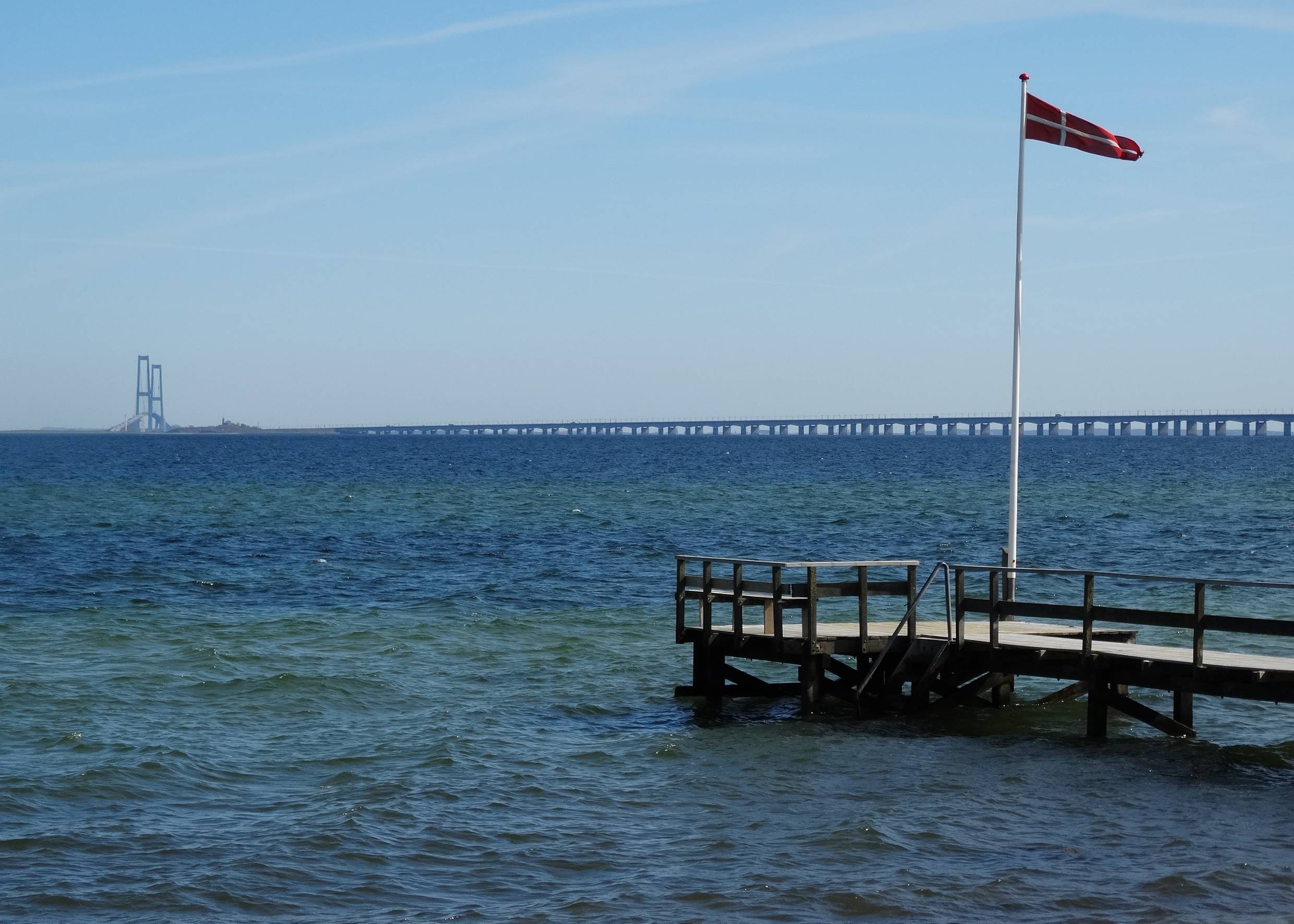 Steg mit dänischer Fahne, dahinter ein lange Brücke