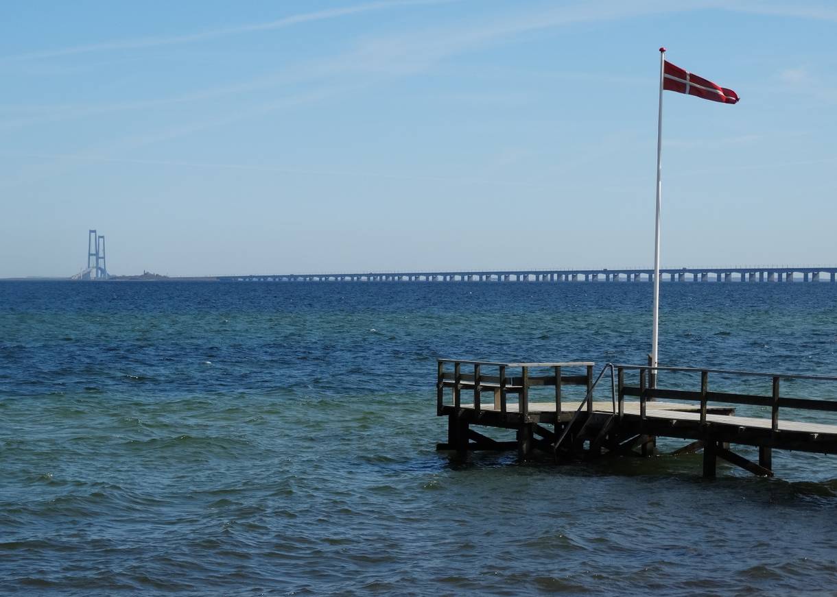 Steg mit dänischer Fahne, dahinter ein lange Brücke