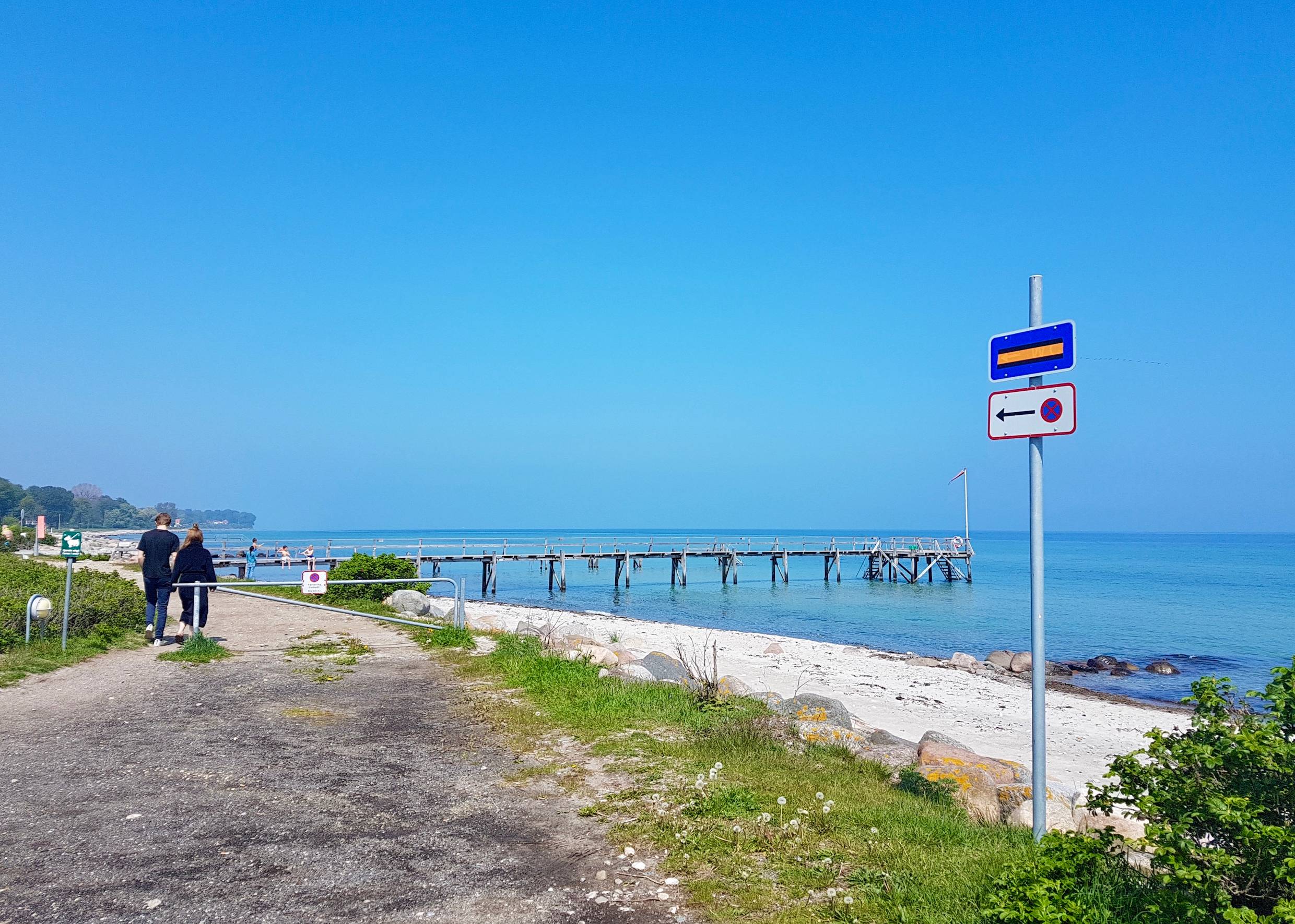 Strandpromenade mit einen Pärchen, am Strand ein Badesteg