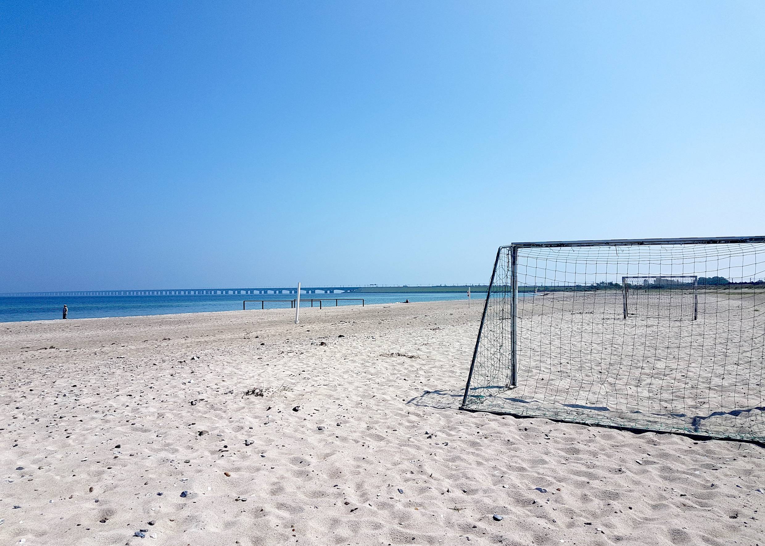 Breiter Sandstrand mit Fußballtoren, im Hintergrund die Storebæltsbroen