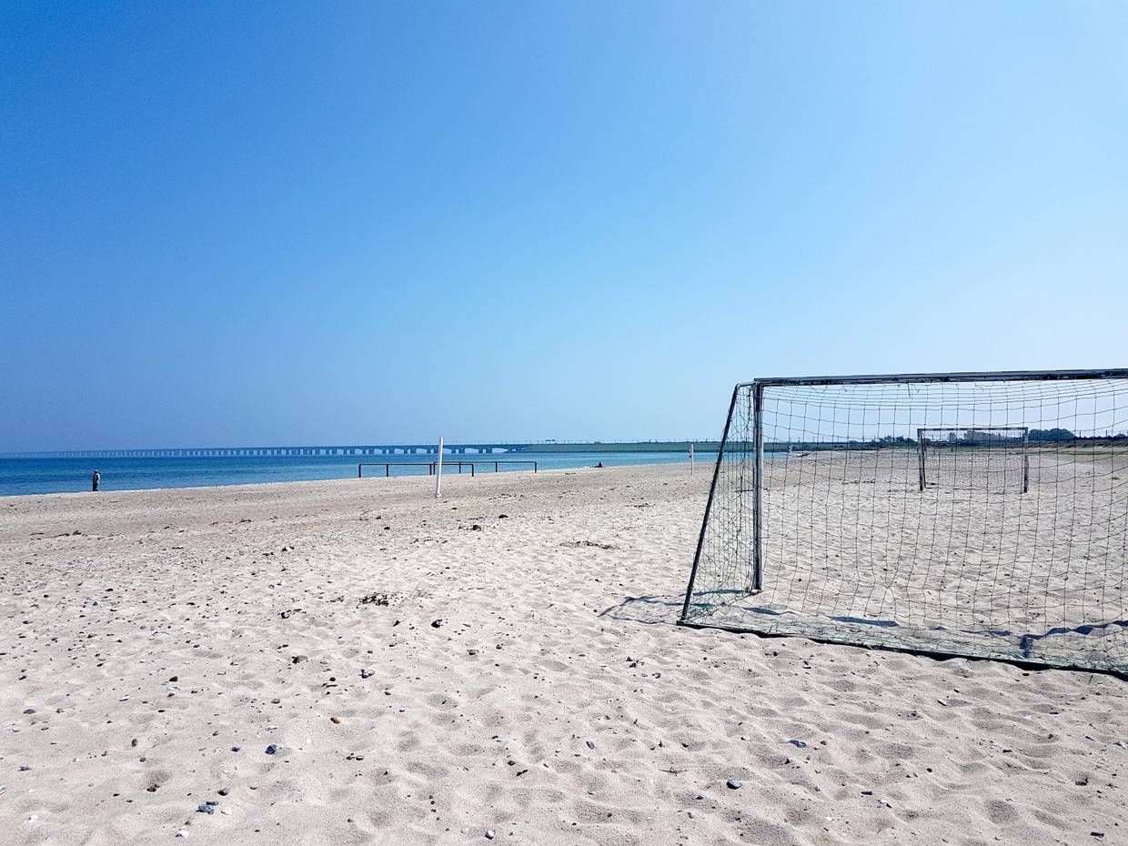 Breiter Sandstrand mit Fußballtoren, im Hintergrund die Storebæltsbroen